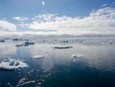 Icebergs float off the port of Ilulissat, Greenland under cloudy sky