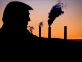 Black silhouette against sunset sky of man on left side of screen facing several belching smokestacks